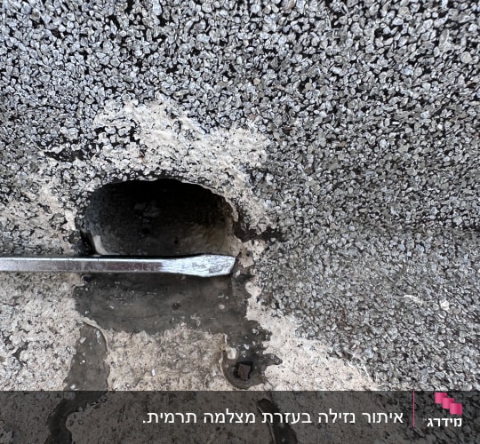 חור בקיר עם כלי מתכת לאיתור נזילות